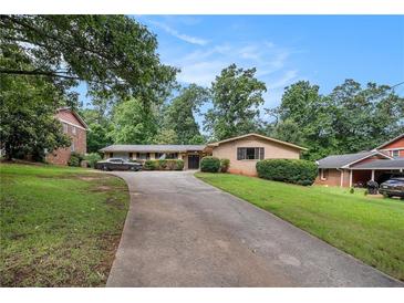 Ranch style home featuring a long driveway, brick facade, manicured shrubs, and mature trees at 3946 Flakes Mill Rd, Decatur, GA 30034