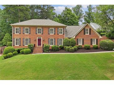 Charming brick home featuring a well-manicured lawn, mature trees, and traditional shutters at 5545 Durrett Dr, Atlanta, GA 30338
