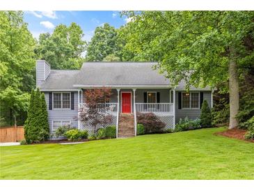 Charming home featuring a well-manicured lawn, cozy front porch, and vibrant red front door at 5761 E Emerald Oaks Ln, Acworth, GA 30102