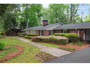 Charming brick home with a landscaped front yard featuring mature trees and colorful azaleas at 302 Chinquapin Sw Dr, Marietta, GA 30064