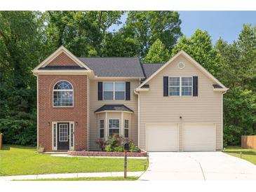 Charming two-story home featuring a manicured lawn, brick accents, and a two-car garage at 4608 Treasure Ct, Forest Park, GA 30297