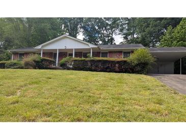 Charming brick home with a covered porch and carport, nestled in a lush green yard with mature trees at 4889 Fairforest Dr, Stone Mountain, GA 30088