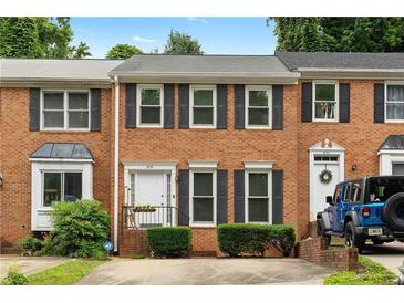 Charming brick townhome featuring black shutters, trimmed bushes and a white door with black handrails and a flower pot at 2779 Bentley Se Pl, Marietta, GA 30067