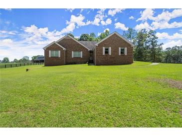 A charming brick home has a large lawn, mature trees and a barn in the background at 3950 Chattahoochee Rd, Cumming, GA 30041