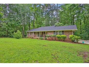 Charming brick ranch home featuring a well-manicured lawn and mature trees at 4774 Saint Bernard Sw Dr, Lilburn, GA 30047