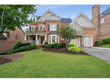 Beautiful brick home boasts an inviting front porch, manicured lawn, and attached two-car garage at 3250 Seven Oaks Dr, Cumming, GA 30041