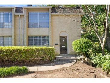 Charming townhome featuring a classic brick facade, manicured shrubs, and large windows providing ample natural light at 5400 Roswell Rd # Apt E6, Sandy Springs, GA 30342
