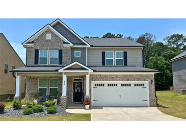 Charming two-story brick home boasts a well-manicured lawn, two car garage, and covered porch at 113 Canal St, Hampton, GA 30228