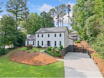 Charming white two-story home featuring manicured landscaping and a spacious driveway at 2885 Laurel Green Ct, Roswell, GA 30076