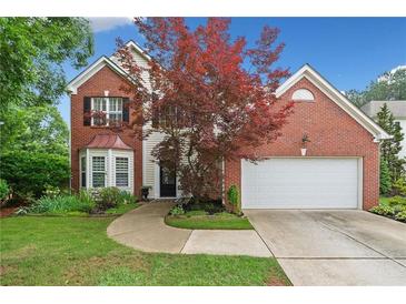 Charming two-story brick home featuring manicured lawn, two-car garage, and mature landscaping at 1100 Carrington Pkwy, Villa Rica, GA 30180