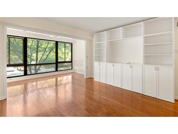 Bright living room with a wall of built-in shelving and cabinets plus a large picture window at 1800 Clairmont Lk # 216, Decatur, GA 30033