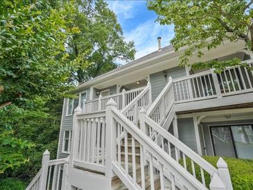 Charming two-story condo with light gray siding and white trim, nestled among lush greenery under a bright blue sky at 212 Abingdon Way, Atlanta, GA 30328