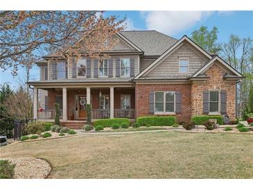 Charming two-story home with a brick and stone facade, covered porch, manicured lawn, and professional landscaping at 1870 Marcia Overlook Dr, Cumming, GA 30041