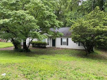 Quaint one-story home with green lawn and mature trees offering shade and privacy at 425 Rockingham Ln, Woodstock, GA 30189
