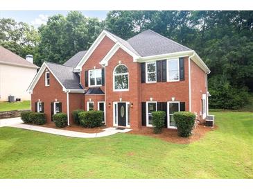 Charming two-story red brick home featuring black shutters and a well-manicured front lawn at 3932 E Saddle Ridge Dr, Lithonia, GA 30038