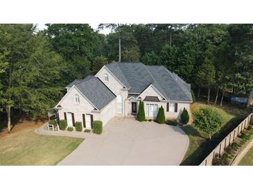 Stunning two-story brick home featuring a well-manicured lawn, a circular driveway, and lush, mature landscaping at 255 Carriage Station Dr, Lawrenceville, GA 30046