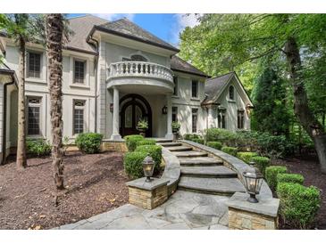 Elegant home with a stone walkway, manicured shrubs, and a charming balcony above the arched entryway at 760 River Gate Dr, Atlanta, GA 30350