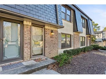 Charming townhome featuring brick facade and dark trim windows, complemented by lush green landscaping at 162 Lablanc Nw Way, Atlanta, GA 30327