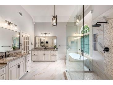 Bright bathroom featuring double vanities, soaking tub, and glass enclosed shower with rain shower head at 5173 Brendlynn Dr, Suwanee, GA 30024
