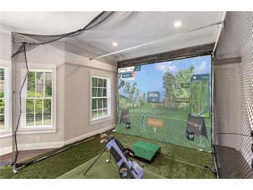 Indoor golf simulator room featuring artificial turf, a large projector screen, and netting for an immersive experience at 5173 Brendlynn Dr, Suwanee, GA 30024