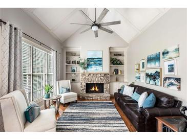 Cozy living room with a stone fireplace, vaulted ceiling, and plush seating arrangement at 5173 Brendlynn Dr, Suwanee, GA 30024