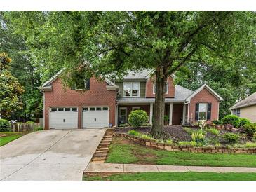 Charming brick home featuring a well-manicured lawn and a two-car garage at 107 W Point Trl, Woodstock, GA 30189