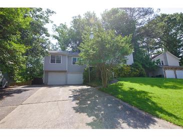 Split-level home featuring a front yard and a two-car garage nestled within a lush, green surrounding at 1112 Mountain Springs Nw Dr, Kennesaw, GA 30144