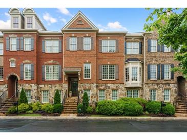 Beautiful brick townhome featuring stone accents, shutters, and manicured landscaping at 1227 Parkside Village Nw Dr, Marietta, GA 30060