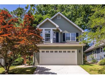 Charming two-story home with a well-maintained lawn and a two car garage and colorful tree at 1100 Ashbury Dr, Decatur, GA 30030