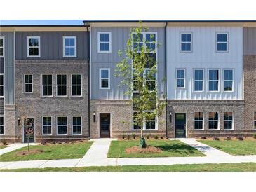 Modern townhome featuring mixed material elevation, a well manicured yard, and a newly planted tree at 2971 Beaconwood Ct, Lawrenceville, GA 30043