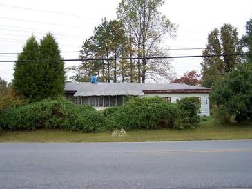 Modest single-story home with mature landscaping and a screened-in porch, offering curb appeal and outdoor living space at 688 Collinsworth Rd, Palmetto, GA 30268