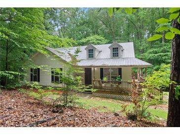 Charming cottage-style home featuring a metal roof and a covered front porch, nestled among mature trees at 345 Jesse Martin Trl, Canton, GA 30115