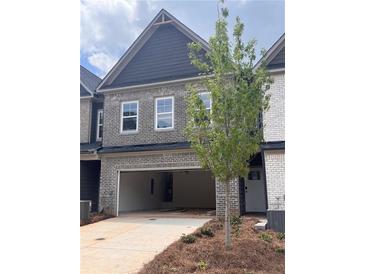 Two-story townhome with a brick facade, gray siding, a large two-car garage, and professional landscaping at 3106 Marbella Cir # 3, Kennesaw, GA 30152