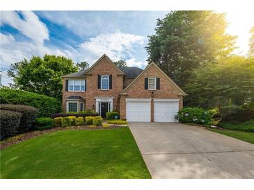 Charming brick home featuring a two-car garage, manicured lawn, and lush landscaping at 540 Shale Ct, Alpharetta, GA 30022
