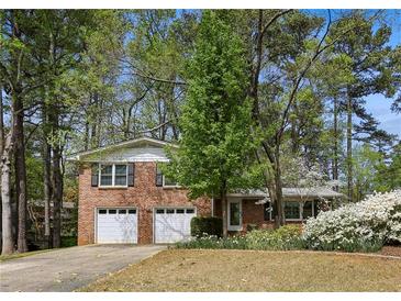 Charming brick home featuring a two-car garage and a beautifully landscaped front yard with mature trees at 2516 Cherry Hill Ln, Atlanta, GA 30360