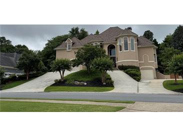 Elegant tan two-story home featuring a circular driveway and lush landscaping at 2503 Regency Lake Dr, Marietta, GA 30062