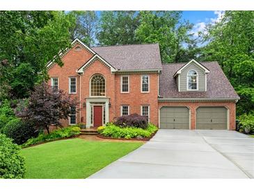 Lovely brick home with a well-manicured lawn, lush trees, and an attached two-car garage at 3915 Woolbridge Way, Marietta, GA 30062