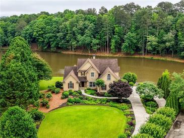 Beautiful two-story home with manicured lawn and lush landscaping overlooking a serene lake at 2675 Portabella Ln, Cumming, GA 30041