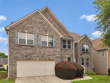 Charming two-story home features a grey brick exterior, well-manicured lawn, and a two-car garage at 3430 Grand Manor Trl, Snellville, GA 30039