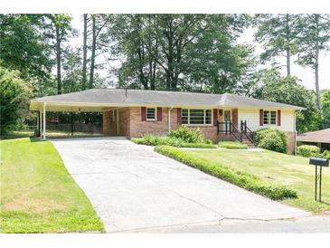 Charming brick ranch home with a long driveway and a covered carport nestled among mature trees at 2614 Princess Se Ln, Marietta, GA 30067