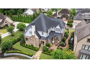Stunning home with a stone and brick exterior, manicured lawn, and elegant landscaping provides incredible curb appeal at 4224 Dogwood Bend Park, Berkeley Lake, GA 30096