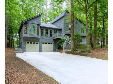 Charming gray two-story home with a two-car garage and a long driveway surrounded by lush trees at 3966 N Indian Nw Cir, Kennesaw, GA 30144