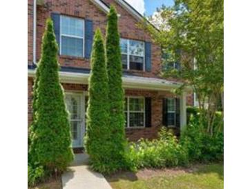 Charming brick home featuring mature trees and a well-manicured lawn and a sidewalk at 6684 Crane Ave, Fairburn, GA 30213