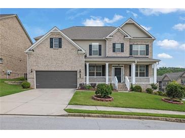 Charming brick home with a well-manicured lawn, covered porch, and two-car garage in a suburban neighborhood at 56 Addison Woods Dr, Sugar Hill, GA 30518