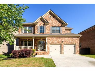Charming two-story brick home with a well-manicured lawn, covered porch, and a two-car garage on a sunny day at 1021 Reddy Farm Rd, Grayson, GA 30017