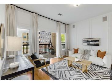 Bright living room boasts natural light from the balcony with a modern sofa and stylish black and white rug at 870 Inman Village Ne Pkwy # 305, Atlanta, GA 30307
