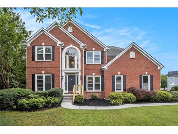 Beautiful two-story brick home with a well-manicured lawn, garden and mature landscaping at 2330 Springmonte Pl, Cumming, GA 30041