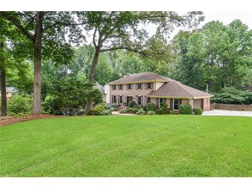 Charming two-story brick home with lush landscaping and mature trees, creating a welcoming curb appeal at 4366 Cedar Wood Sw Dr, Lilburn, GA 30047