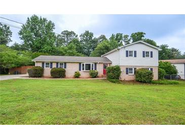 Charming two-story home featuring a lush green lawn and mature landscaping at 456 Harmony Grove Rd, Lilburn, GA 30047