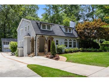 Charming two-story home featuring a stone-arched entry, a well-manicured lawn, and mature trees at 1195 Cameron Ct, Atlanta, GA 30306